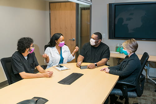 Male and female laboratorians sitting at a table in a discussion.
