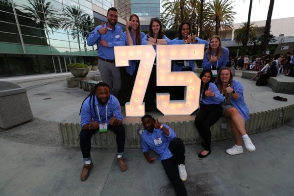 ADLM staff members sitting around a giant number 75 at the 2023 AACC Annual Scientific Meeting opening mixer.