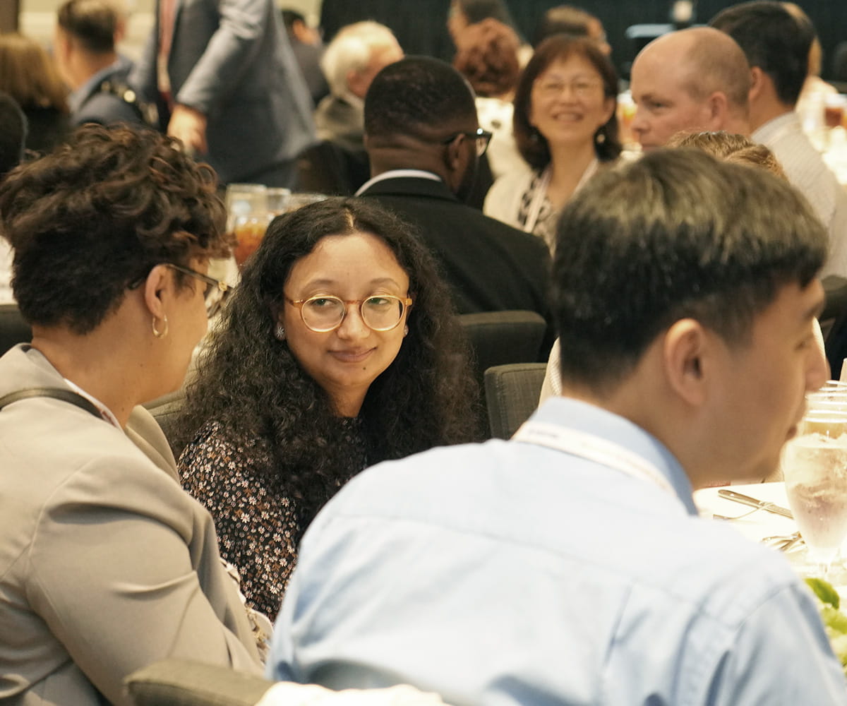 A group of people sitting at a table and speaking with each other