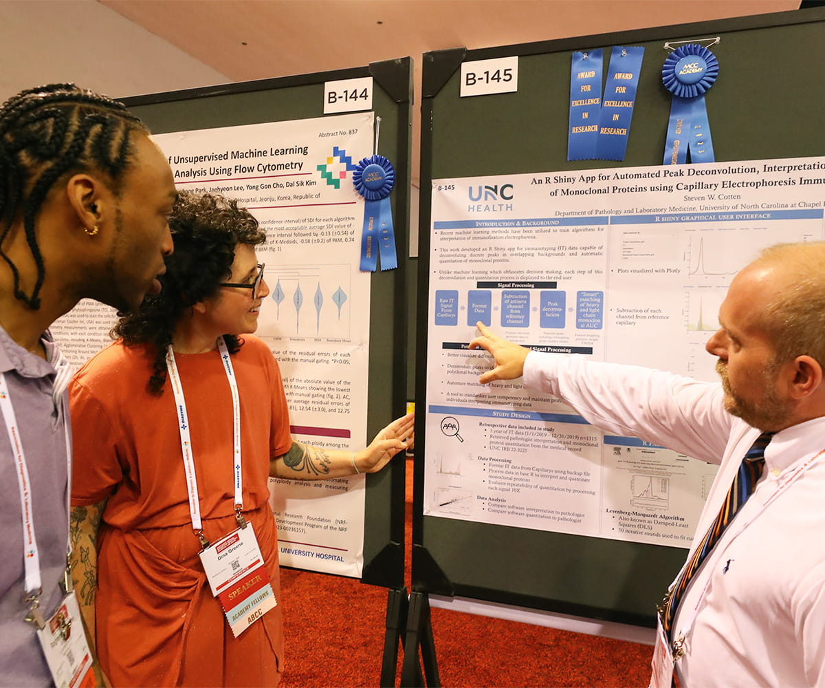 A woman and two men standing in front of a scientific poster and pointing to it