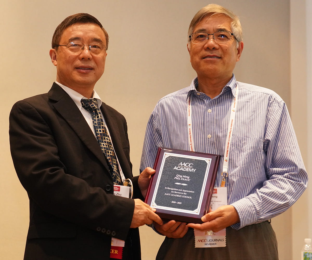 Two men posing for picture while holding a plaque