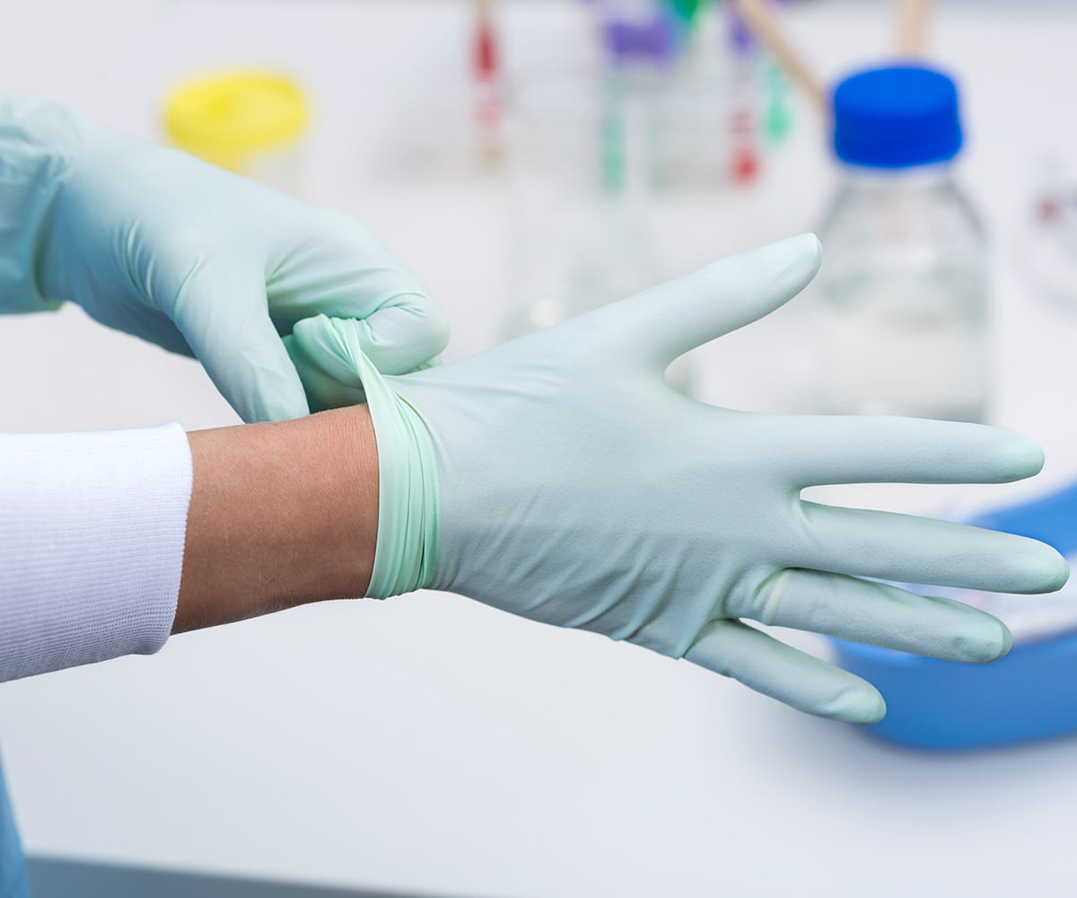 Hands in medical gloves working with container