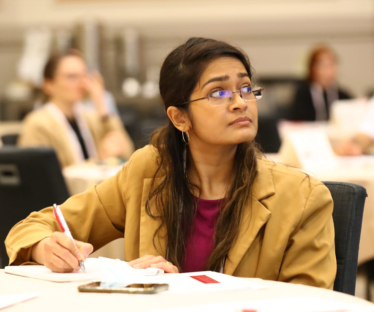 Woman sitting at table taking notes and looking up