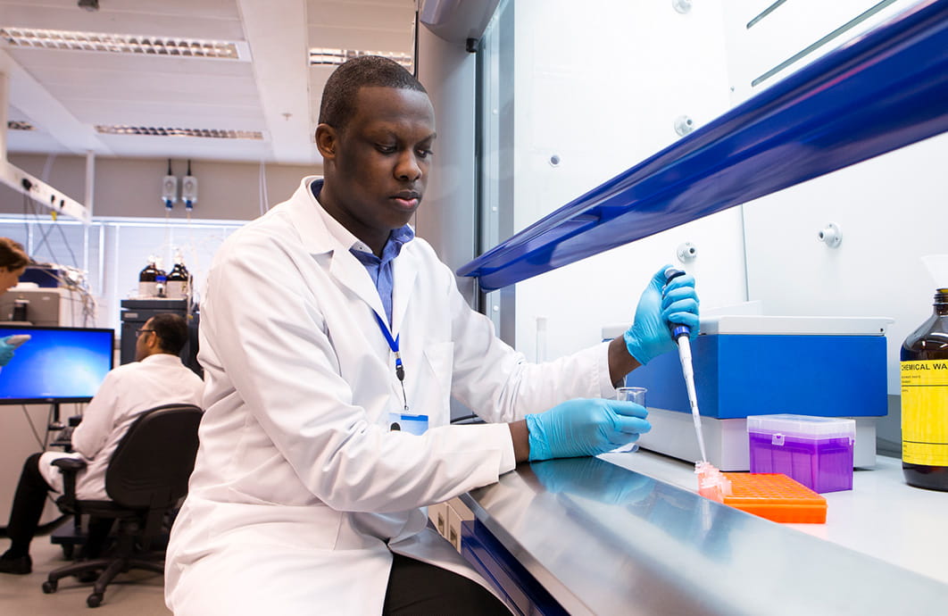 A male laboratorians holding a pipette.
