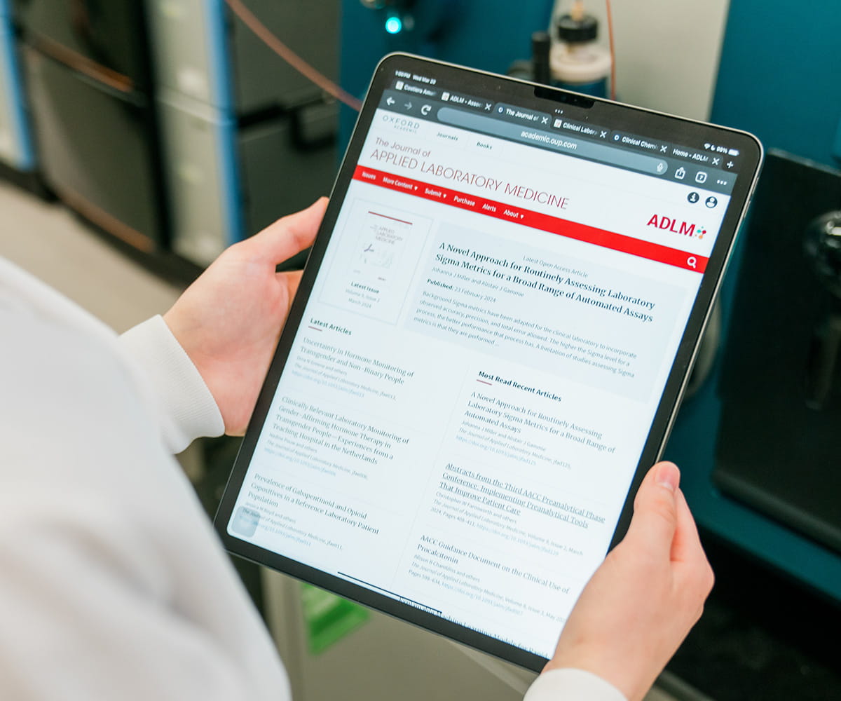 Hands holding an iPad with a Journal of Applied Laboratory Medicine