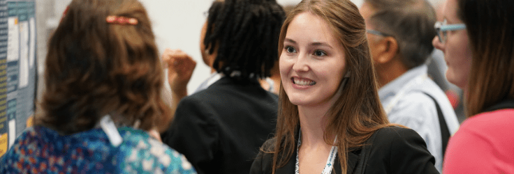 Young woman at Annual Scientific Meeting smiling and talking to older woman