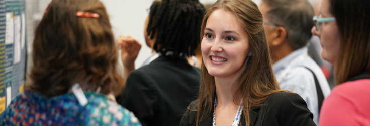 Young woman at Annual Scientific Meeting smiling and talking to older woman