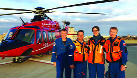 Four healthcare workers standing in front of a helicopter ambulance 
