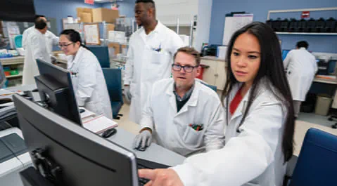 Laboratorians looking at a computer screen