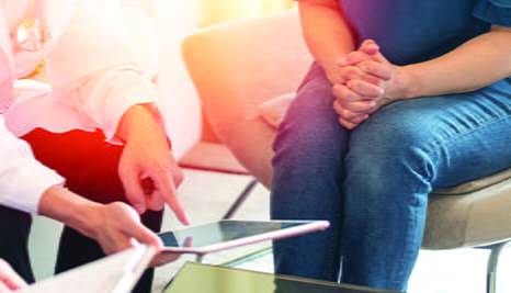 A doctor and and patient sitting while the doctor points to a tablet