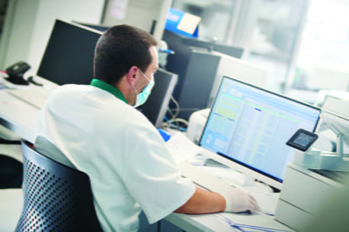 A male laboratorian sitting at a desk on a computer