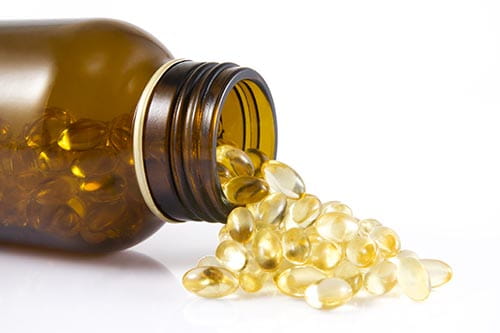 A brown vitamin bottle on its side with vitamins spilling out