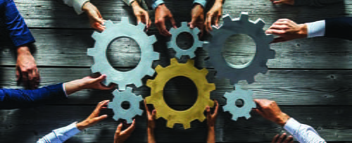 Several hands holding gears and putting them together in the center.