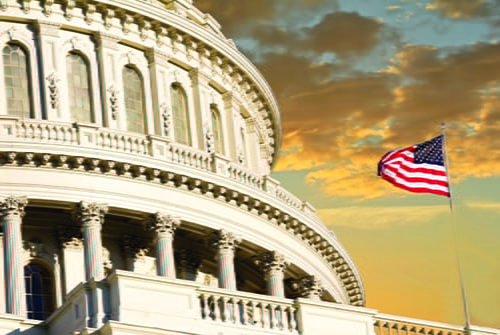 United States Capital with an American flag waving right next to it.