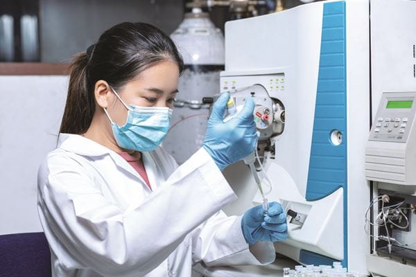A laboratorian pipettes in the lab.