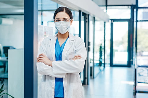 A masked, female laboratorian posing in a lab