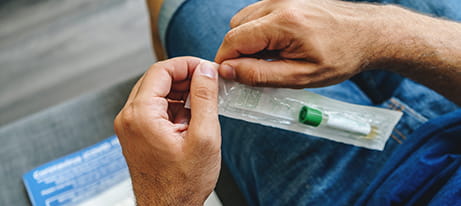 Man's hands opening a Covid-19 Home Test
