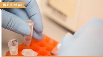 Gloved hand holding a vial.