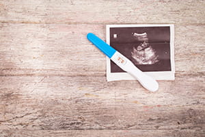 A screenshot of an ultrasound with a pregnancy test laying on top