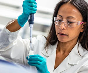 Female laboratorian injecting fluid into a testing tube